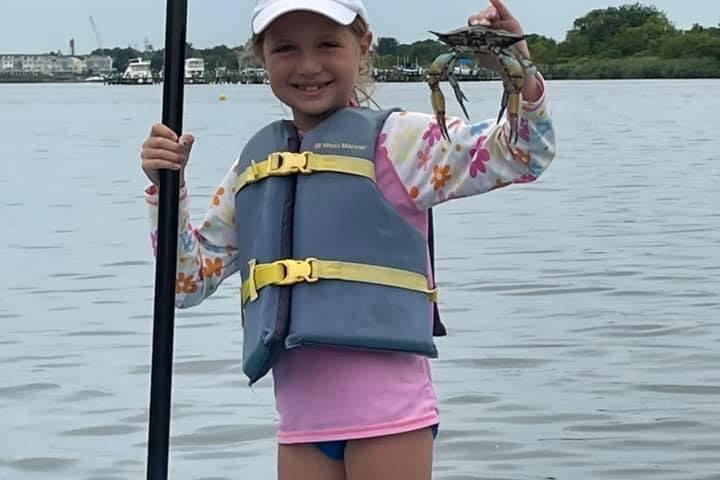 a little girl standing next to a body of water