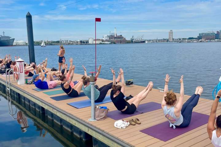 a group of people sitting on a dock next to a body of water